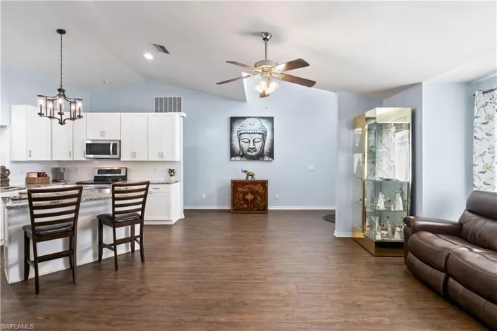 Kitchen featuring white cabinetry, stainless steel appliances, hanging light fixtures, and dark hardwood / wood-style flooring