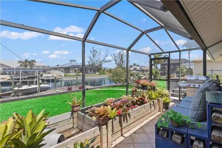 View of patio / terrace with a water view, glass enclosure, and a boat dock