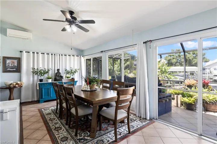 Tiled dining room featuring ceiling fan, vaulted ceiling, and a wall unit AC