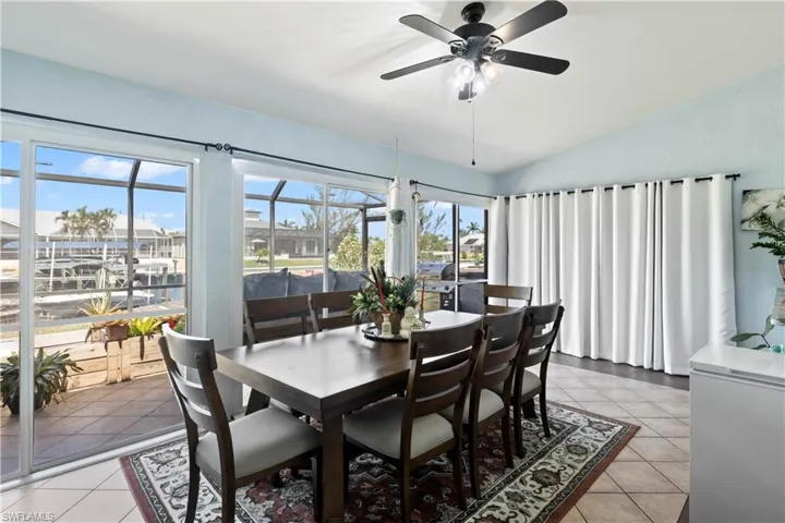Tiled dining area featuring ceiling fan and vaulted ceiling