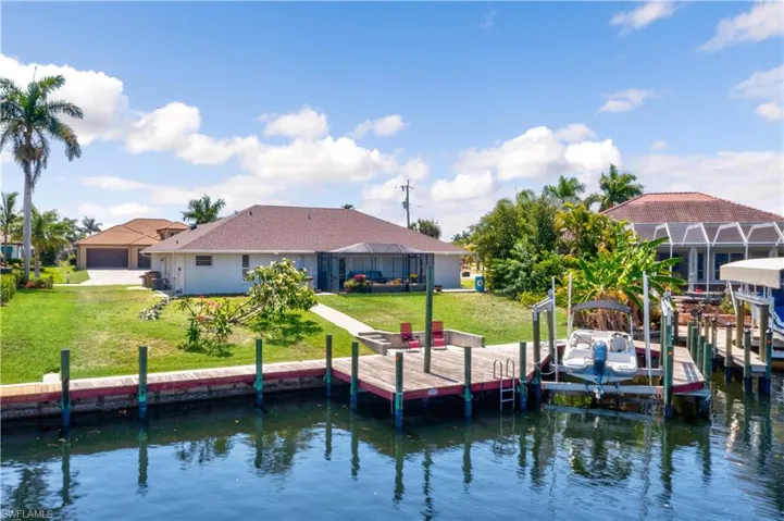 Dock area with a lawn, a water view, and glass enclosure