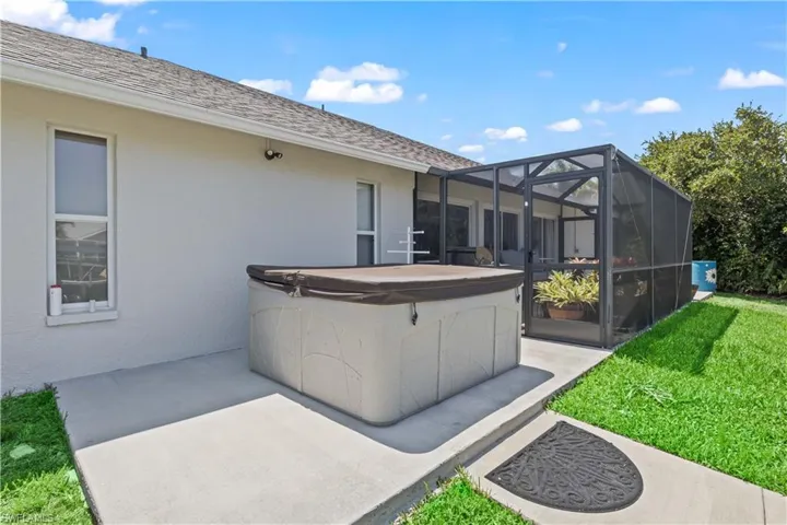 View of patio with a hot tub and glass enclosure