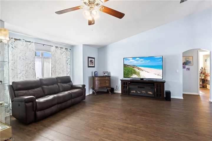 Living room with vaulted ceiling, ceiling fan, and dark hardwood / wood-style flooring