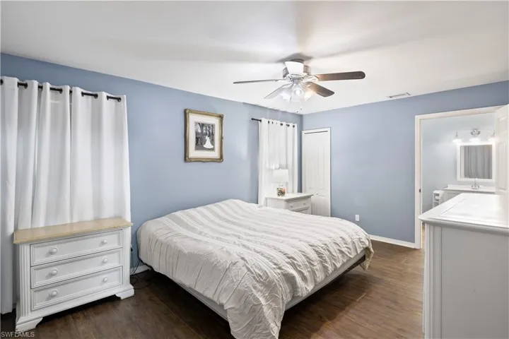 Bedroom featuring ensuite bath, dark wood-type flooring, and ceiling fan