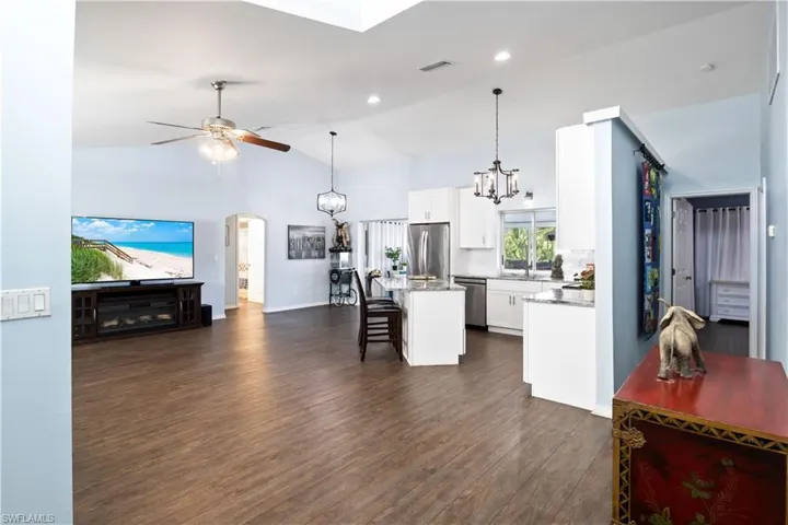 Kitchen with lofted ceiling, a kitchen island, white cabinetry, and stainless steel appliances