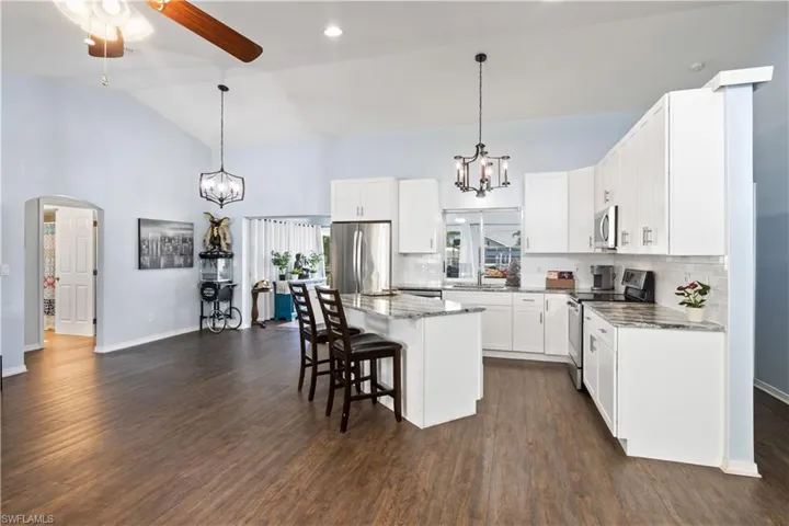 Kitchen with a center island, appliances with stainless steel finishes, vaulted ceiling, and dark hardwood / wood-style floors