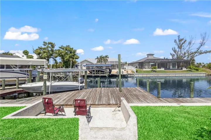 Dock area featuring a water view, a lawn, and a lanai