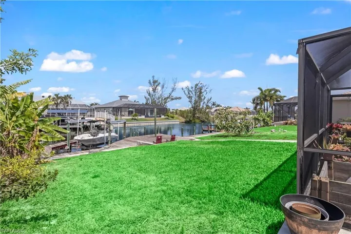 View of yard featuring a dock, a water view, and glass enclosure