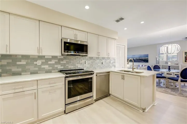 Kitchen with a peninsula, appliances with stainless steel finishes, light countertops, and a sink