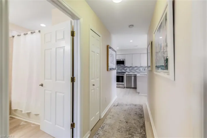 Corridor featuring baseboards, recessed lighting, a sink, and light wood-style floors