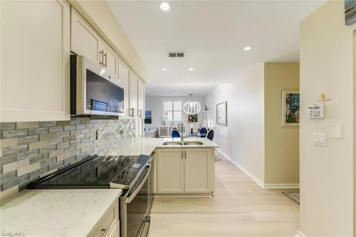 Kitchen with tasteful backsplash, visible vents, appliances with stainless steel finishes, a peninsula, and a sink