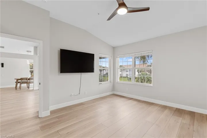 Unfurnished living room with ceiling fan, light hardwood / wood-style floors, and vaulted ceiling
