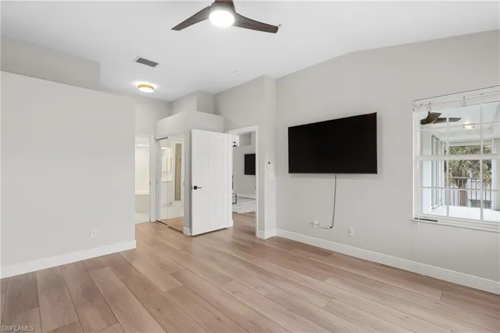 Unfurnished living room featuring ceiling fan, light wood-type flooring, and vaulted ceiling
