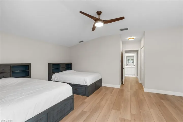 Bedroom with ceiling fan, light wood-type flooring, and vaulted ceiling
