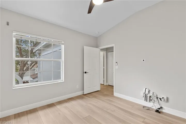 Unfurnished room featuring ceiling fan, light wood-type flooring, and vaulted ceiling