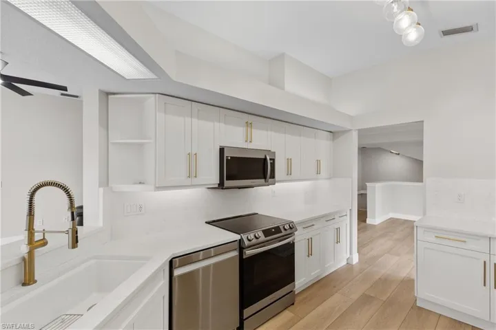 Kitchen with white cabinetry, sink, appliances with stainless steel finishes, and light hardwood / wood-style flooring