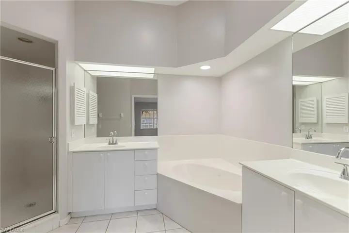 Bathroom featuring tile patterned floors, vanity, separate shower and tub, and a skylight