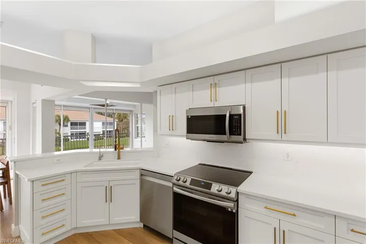 Kitchen featuring sink, light wood-type flooring, white cabinetry, kitchen peninsula, and stainless steel appliances