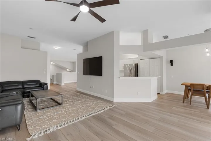Living room featuring a towering ceiling, light hardwood / wood-style flooring, and ceiling fan