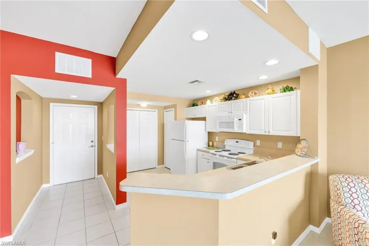 Kitchen with light countertops, white appliances, light tile patterned floors, recessed lighting, and white cabinetry