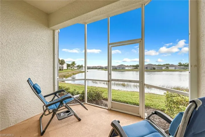 Sunroom / solarium with a textured wall, a water view, a residential view, and carpet flooring