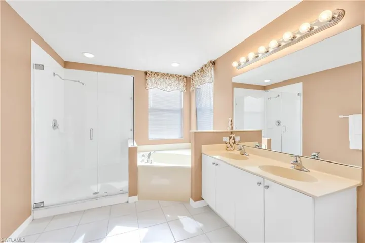 Full bathroom with double vanity, light tile patterned floors, a stall shower, a bath, and recessed lighting