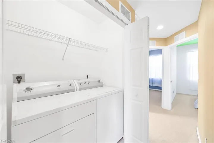 Washroom with light carpet and washing machine and clothes dryer