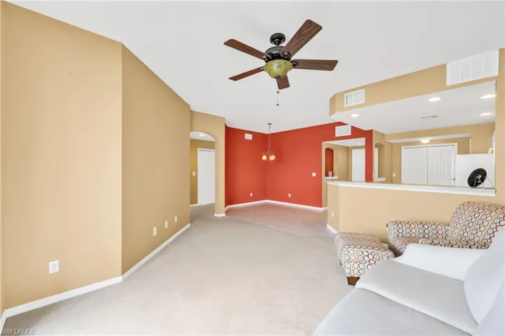 Carpeted living area featuring arched walkways, recessed lighting, a ceiling fan, and tile patterned floors