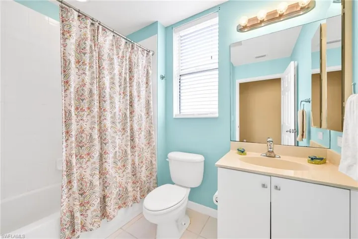 Full bathroom featuring light tile patterned floors, vanity, and shower / bath combo with shower curtain