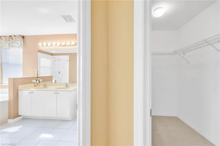 Full bathroom with a spacious closet, double vanity, light tile patterned floors, a bath, and a shower