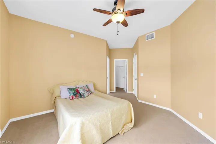 Carpeted bedroom featuring a spacious closet and ceiling fan