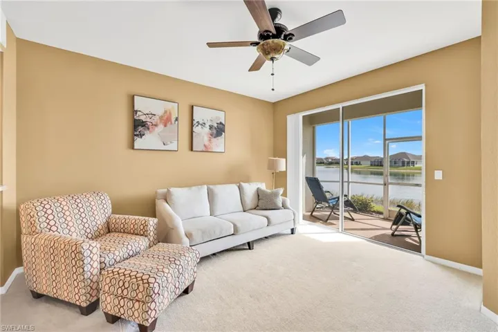 Living room featuring carpet, a ceiling fan, and a water view