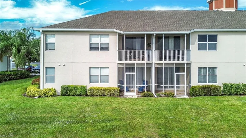 Back of house with a sunroom, stucco siding, a lawn, and a balcony