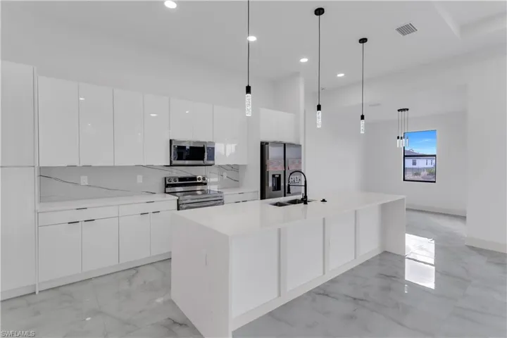 Kitchen with stainless steel appliances, light marble finish flooring, white cabinets, and modern cabinets