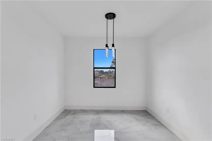 Unfurnished dining area featuring light marble finish flooring and baseboards