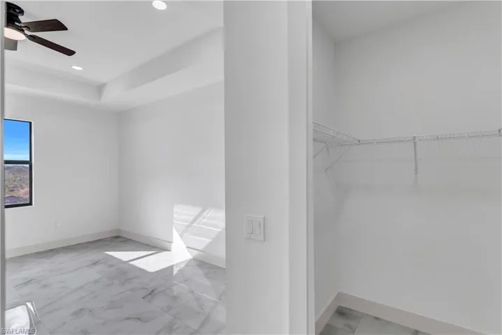 Walk in closet with light marble finish flooring and a ceiling fan