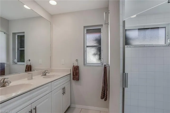 Bathroom featuring tile patterned floors, vanity, and an enclosed shower