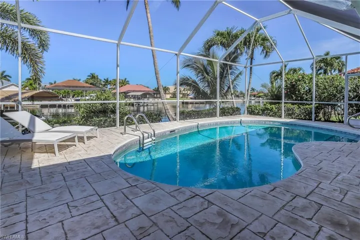 View of swimming pool with glass enclosure, a water view, and a patio