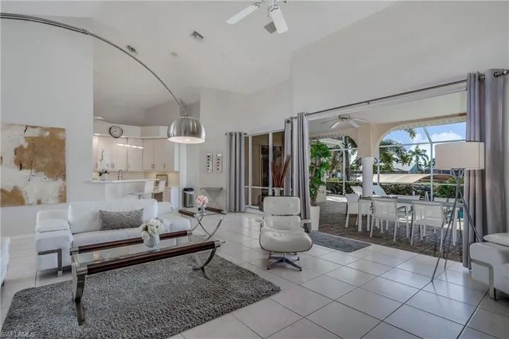 Living room with ceiling fan, high vaulted ceiling, and light tile patterned flooring