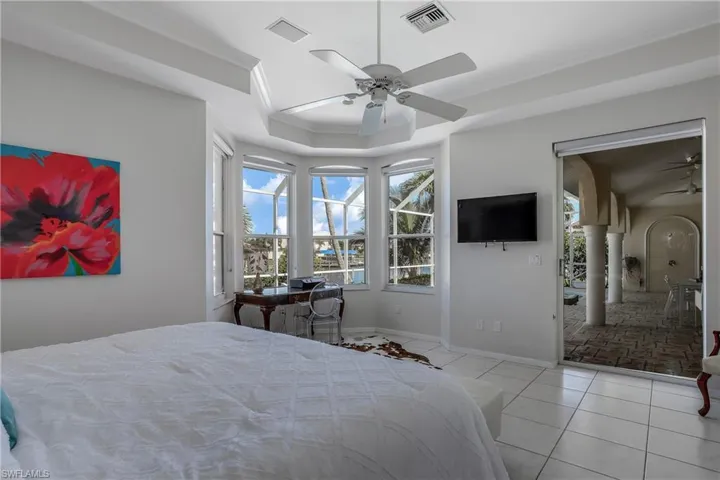 Bedroom with light tile patterned floors, ceiling fan, and crown molding