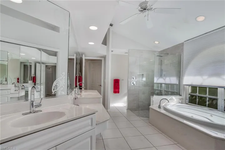 Bathroom with vanity, separate shower and tub, ceiling fan, tile patterned flooring, and lofted ceiling