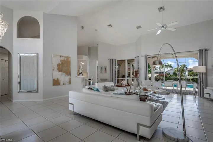 Tiled living room featuring high vaulted ceiling and ceiling fan