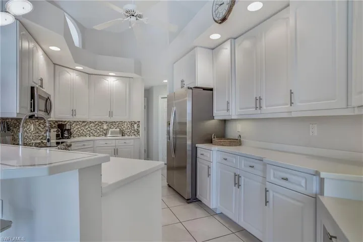 Kitchen featuring light tile patterned floors, stainless steel appliances, white cabinetry, and ceiling fan