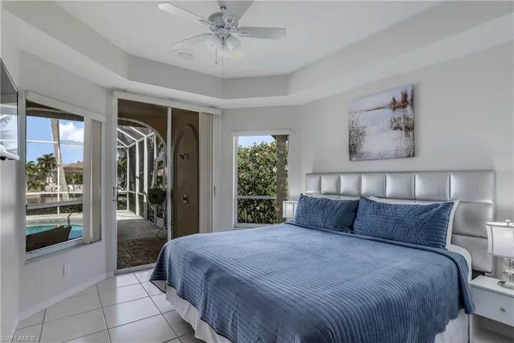 Tiled bedroom featuring access to outside, multiple windows, and ceiling fan