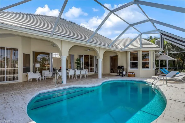 View of swimming pool with glass enclosure, ceiling fan, a patio, and grilling area