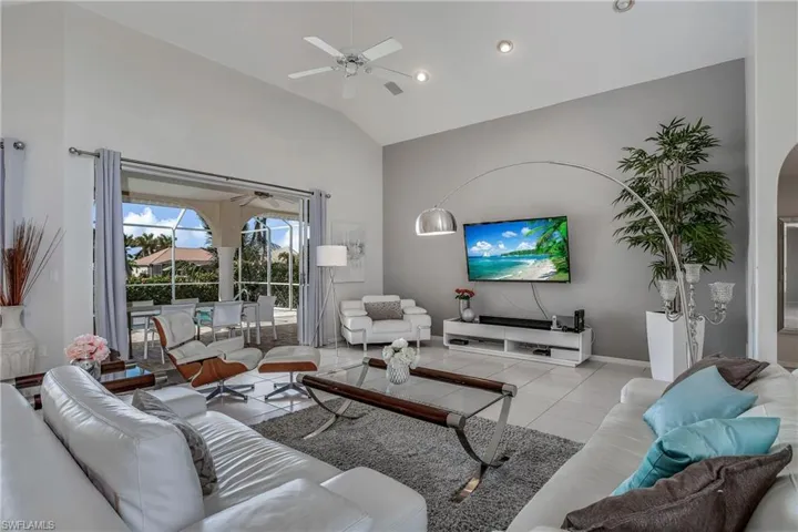 Living room with ceiling fan, light tile patterned flooring, and high vaulted ceiling
