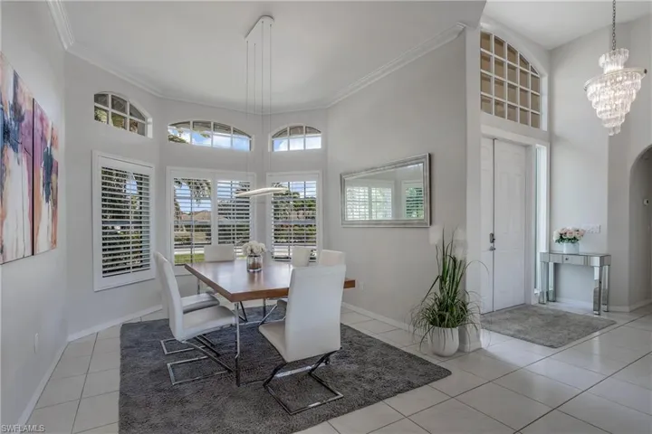 Tiled dining space with a high ceiling, an inviting chandelier, and ornamental molding
