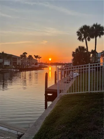 View of dock with a lawn and a water view