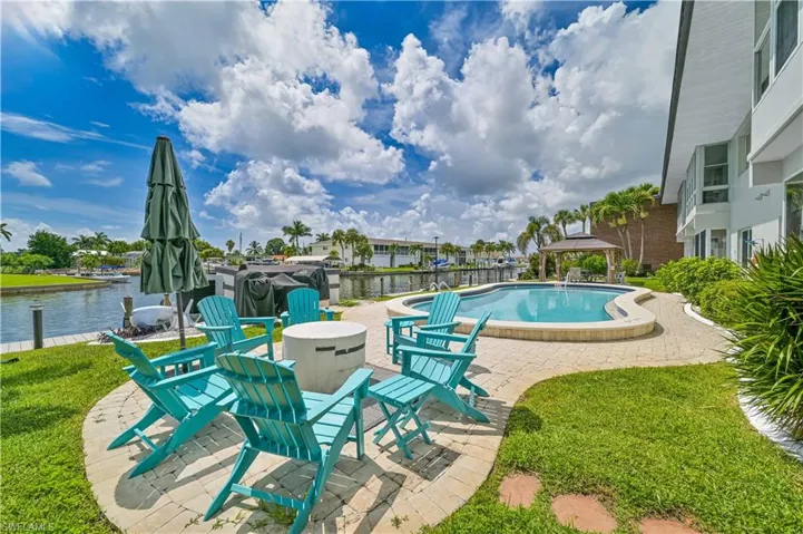 View of swimming pool with a water view, a yard, and a patio