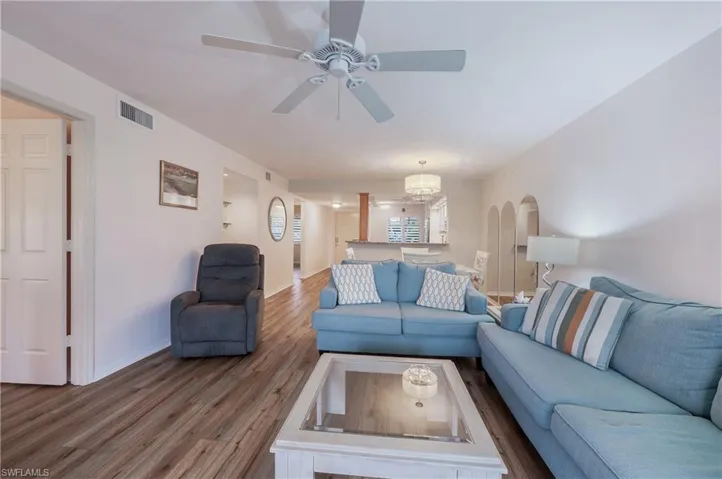 Living room featuring ceiling fan with notable chandelier and hardwood / wood-style floors